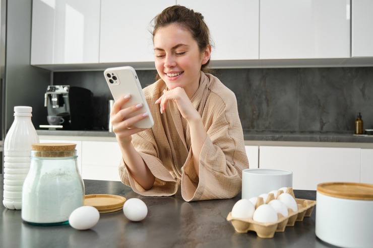 Woman reading a recipe on her phone in the kitchen